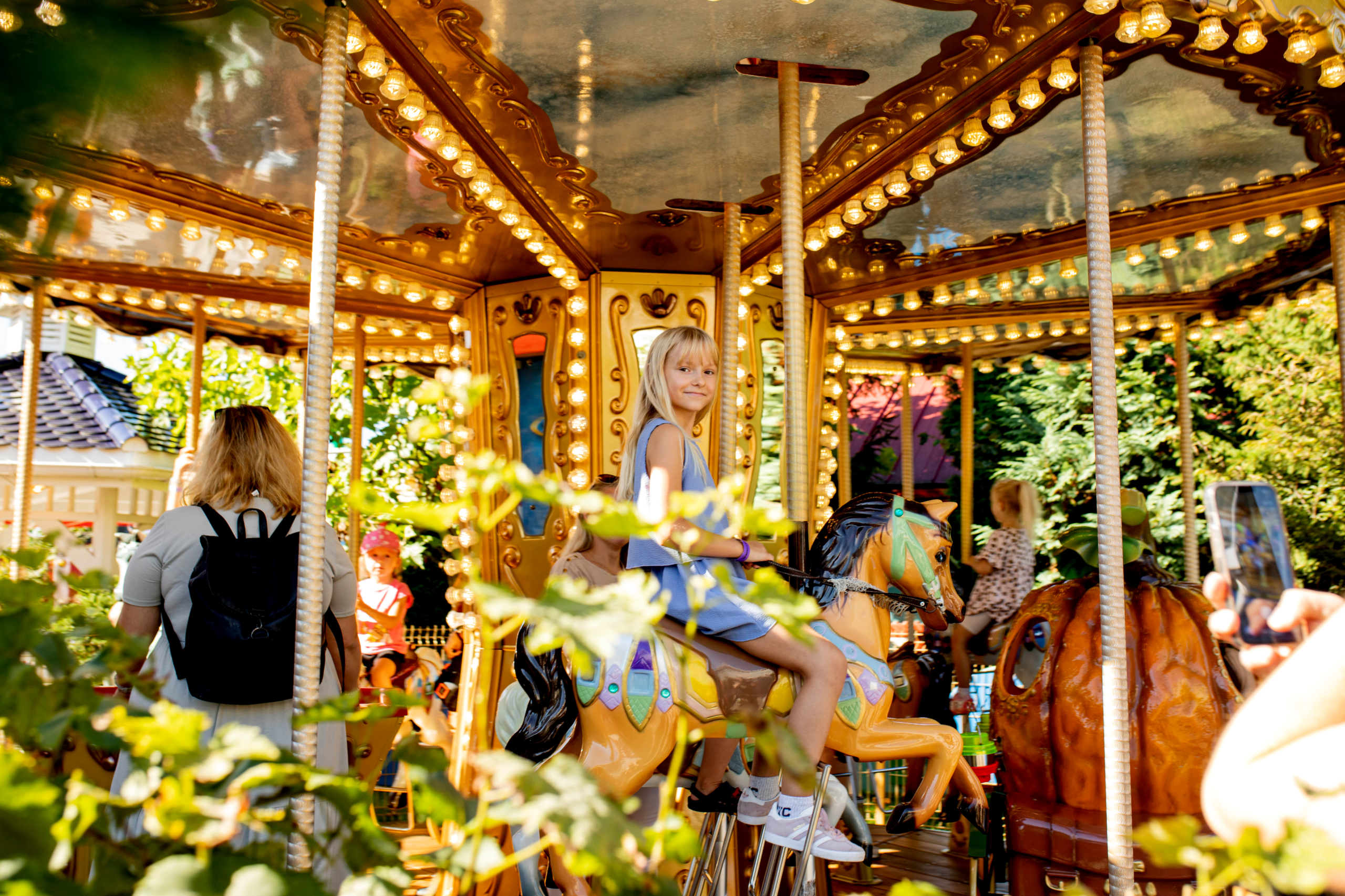 Classic carousel ride experience with Krakow Direct Tours Carousel ride at Energylandia with warm lights, child sitting on a horse on a sunny day.